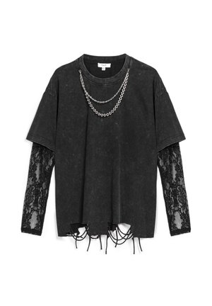 Camiseta negra de gran tamaño con mangas de encaje, dobladillo desgastado y cadena plateada colgando del escote; mezcla de algodón con acabado texturizado.