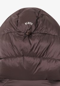 Veste matelassée marron avec une capuche arrondie, en tissu léger, et un cordon de serrage. Présente le logo 'BLKVIS' en blanc à l'avant.