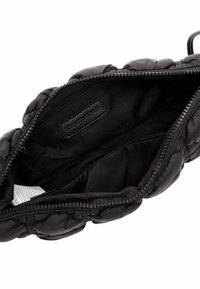Borsa nera trapuntata con interno in nylon liscio, dotata di chiusura con zip e un'etichetta interna. Texture a granuli all'esterno.