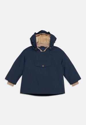 Navy blue children's hooded jacket with beige fleece lining, front flap pocket with button, and ribbed cuffs extending from sleeves.