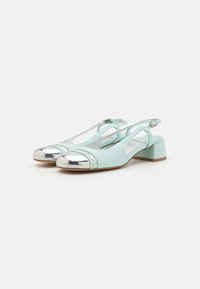 Zelene slingback čevlje z srebrnim lakiranim vrhom in blok peto, ki imajo izrezane detajle in nastavljiv žabic.