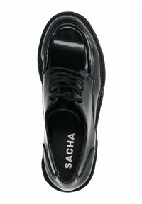 Chaussure en cuir verni noir à lacets avec un bout rond, des surpiqûres ton sur ton et une semelle intérieure marquée. Texture lisse avec une finition brillante.