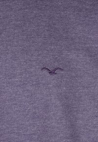 Lila Sweatshirt mit weicher Textur, ausgestattet mit einem kleinen gestickten Logo in einem leicht dunkleren Lila. Schlichtes, unaufgeregtes Design.