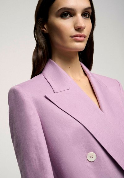 Lilac blazer made from textured fabric, featuring a deep V-neck, wide lapels, and a single button detail at the chest.