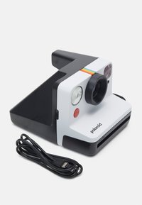 Polaroid instant camera in black and white with a prominent lens, flash, red button, and multicolored stripe; includes USB charging cable.