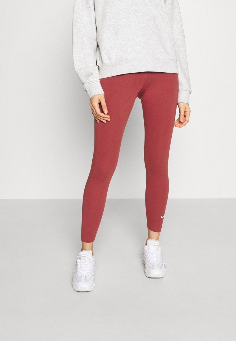 Bordeaux leggings gjorda av stretchigt material, figursydd design, matchade med en grå sweatshirt och vita träningsskor. Nike-logotyp på leggings.