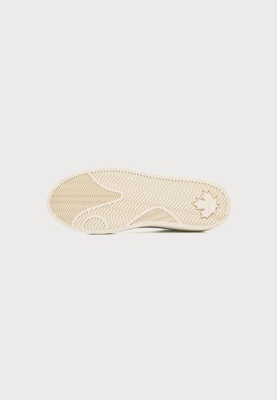 Semelle de chaussure avec bande de roulement en caoutchouc beige présentant un motif en arêtes de poisson et un dessin de feuille d'érable près du talon sur un fond uni.