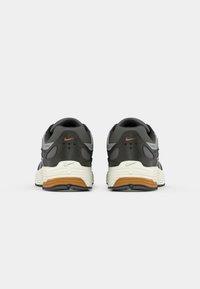 Μαύρα και γκρι αθλητικά παπούτσια με πλέγμα και συνθετικό �επάνω μέρος, λευκή μεσαία σόλα και καουτσούκ σόλα με καφέ λεπτομέρεια.