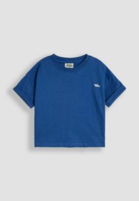 Camiseta de algodón azul de manga corta con escote redondo. Presenta un pequeño gráfico de un tiburón en el lado izquierdo del pecho. Textura suave, diseño casual.