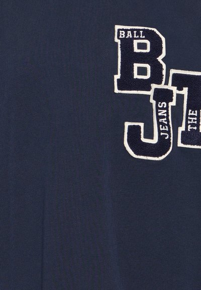 Námornícky bavlnený tkanina s veľkými bielymi vyšitoumi písmenami "B J" a "BALL JEANS" v štýle univerzitného športového oblečenia. Hladká textúra s kontrastnými akcentmi.