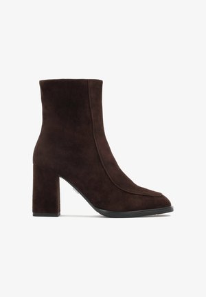 Brauns zamšs potītes zābaks ar blokveida papēdi, ar elegantu dizainu, smailu purngalu un bezšuvēm, kas nodrošina modernu izskatu.