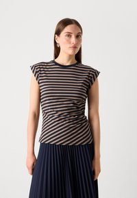 Pruhovaný top s krátkým rukávem v námořnické modři a taupe, s vypasovaným pasem, kulatým výstřihem a měkkou, elastickou tkaninou. Modelka má na sobě plisovanou námořnickou sukni.