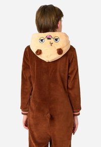 Rjav plišast pajac z mehkim bež kapuco, ki ima risano obraz, majhne ušeske in rep na zadnji strani. Črtasti manšeti v roza in rjavi barvi.