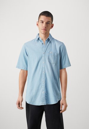 Light blue short-sleeve button-up shirt in denim fabric with a chest pocket, featuring a pointed collar and subtle stitched details.