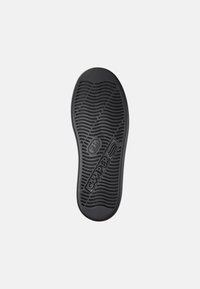 Sole in gomma nera con un motivo a onda, con il logo "Camper" ben visibile e dettagli di presa testurizzati in tutto il design.