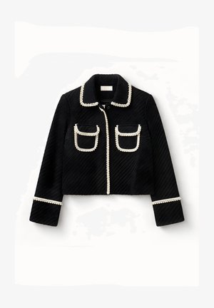 Chaqueta corta negra texturizada con mangas largas, dos bolsillos delanteros con solapa y ribete de cuentas blancas en el cuello, los bolsillos, el frente y los puños.