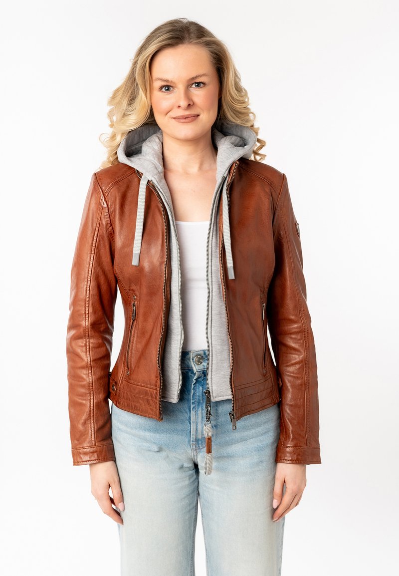 Giacca di pelle marrone con interno felpato grigio a cappuccio, zip frontale, vestibilità slim e tasche frontali, abbinata a jeans blu chiaro.