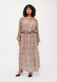 Maxiklänning med off-shoulder-design, blommig paisleymönster i beige och rostfärg, samt ett elastiskt midjeband. Långa ballongärmar.