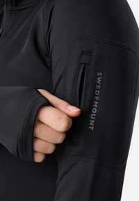 Giacca sportiva nera con tasca con zip sull'avambraccio. Il materiale è liscio e aderente, con un logo visibile sulla parte superiore dell'avambraccio.