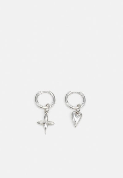 Silver hoop earrings featuring a cross and heart charm. Smooth, shiny texture with a polished finish. Each charm hangs from a secure loop.
