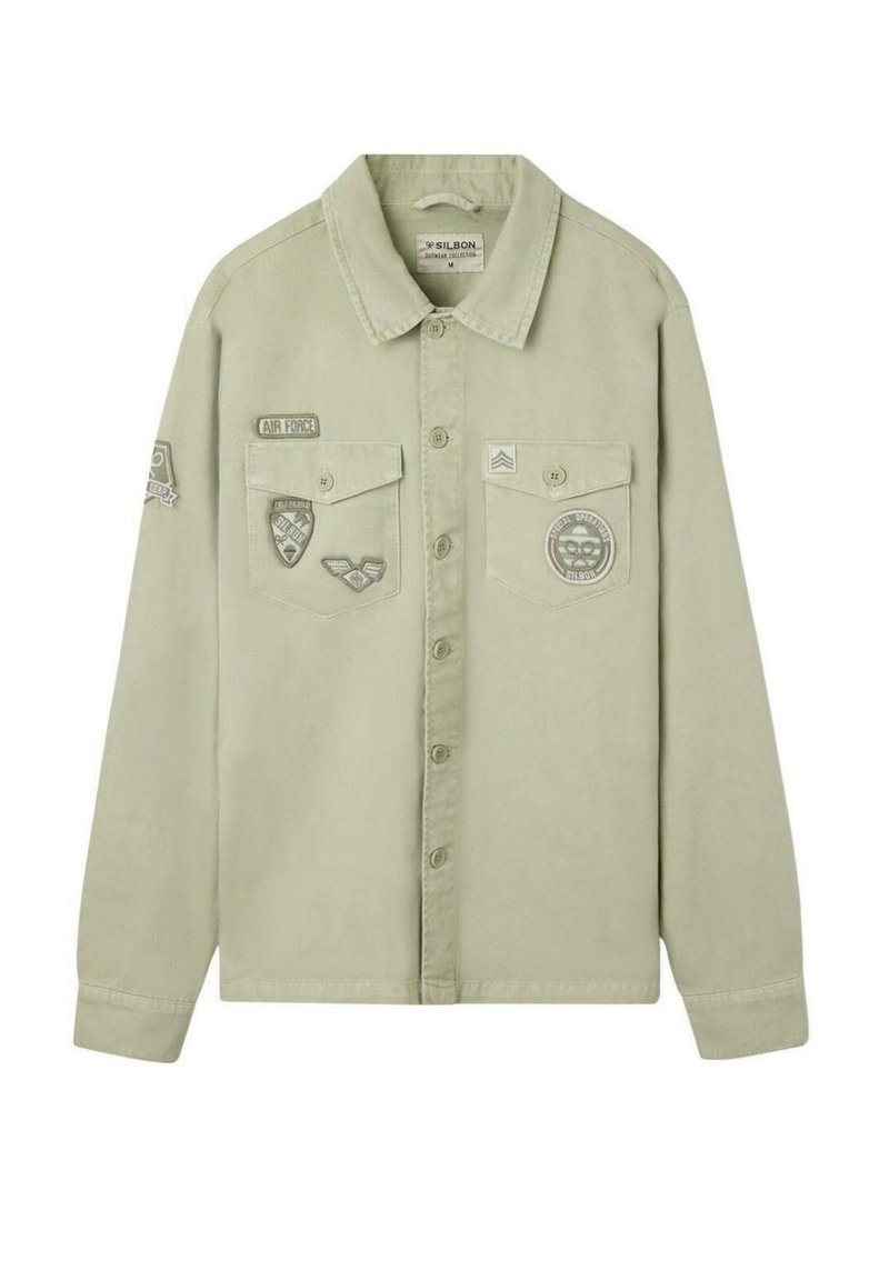 Camisa de botón color khaki claro con mangas largas, dos bolsillos en el pecho y parches y insignias de estilo militar en la parte delantera y en la manga izquierda.