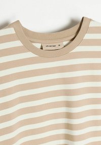 Beżowa i kremowa bluzka z długim rękawem w paski, uszyta z miękkiej bawełny. Charakteryzuje się żebrowanym dekoltem i poziomymi paskami o równej szerokości.