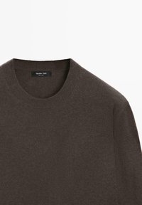 Mörkbrun stickad tröja med rund halsringning, med en slät textur och ribbade kanter. Etiketten säger "Massimo Dutti, tillverkad i Kina."