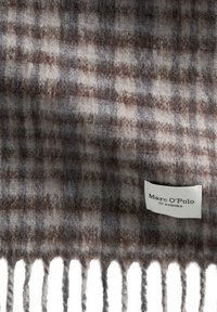 Écharpe en laine avec un motif tartan gris et marron, aux bords frangés et avec une étiquette de marque « Marc O'Polo » en bas.