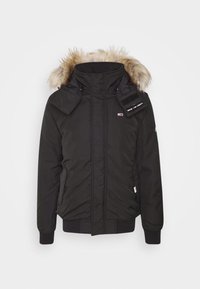 Svart vinterjacka med pälsfodrad huva, frontdragkedja, sidofickor och Tommy Jeans-logotyp på bröstet och ärmen.