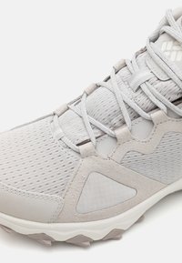 Hellgrauer Sportschuh aus Mesh und Wildleder, mit strukturiertem Obermaterial, mehrlagigem Design und Gummisohle mit Rutschfestigkeitsnoppen.