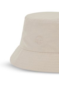 Beige bucket hat i mjukt tyg, med en sydd brätte och en broderad ansiktsdesign på framsidan. Slät textur, enkel silhuett.