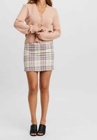 Hellrosa Strickjacke mit geripptem Muster und Rüschenausschnitt, kombiniert mit einem taillierten karierten Minirock in Creme, Lila und Rosatönen.