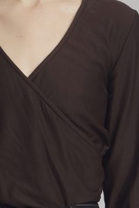 Brown long-sleeve wrap top made of soft fabric features a V-neckline and an asymmetrical design with slight gathering at the side.