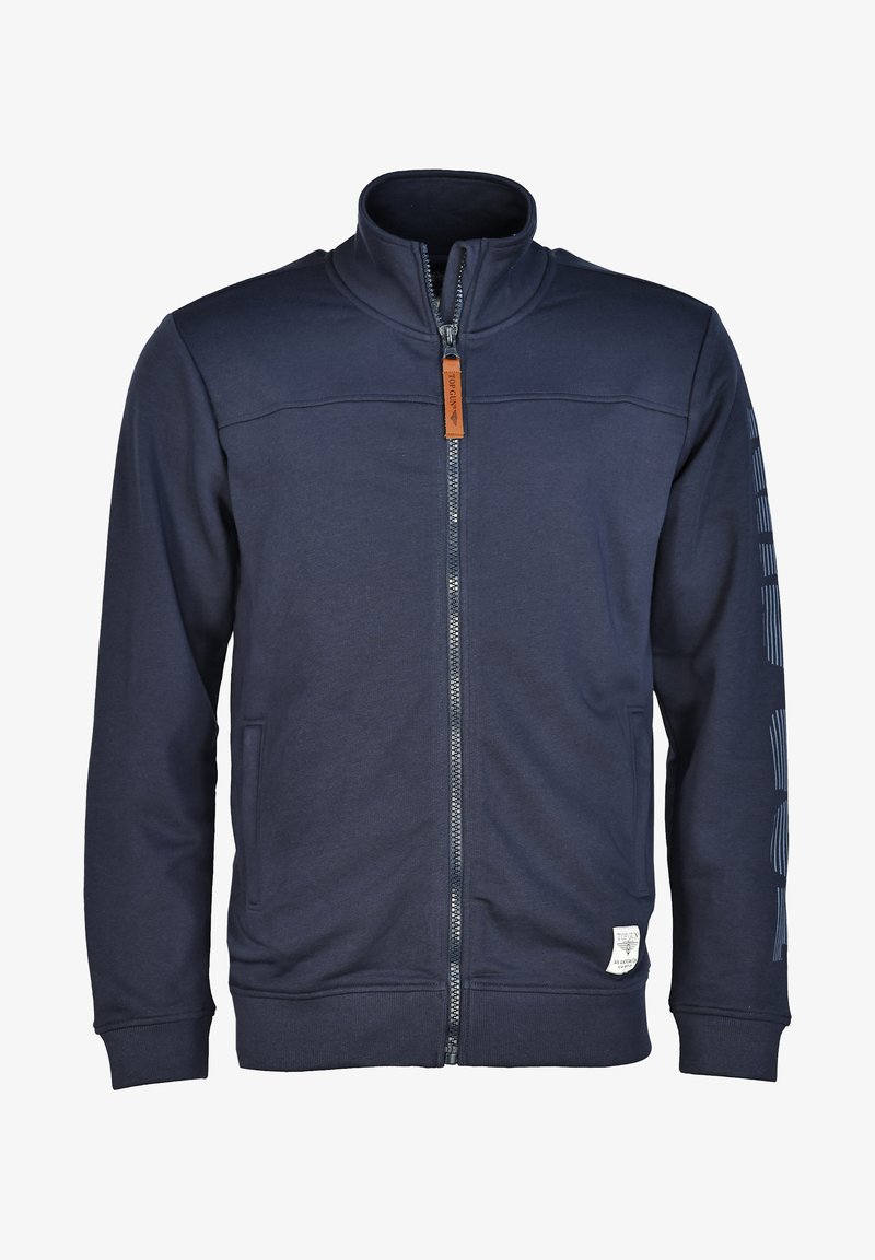 Granatowa kurtka zapinana na zamek z stójką, kieszeniami po bokach, logowanym uchwytem zamka błyskawicznego oraz naszywką z logo na dolnym lewym brzegu i paskach na rękawach.