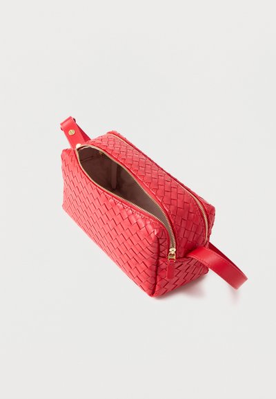 Κόκκινο υφαντό δερμάτινο ορθογώνιο πορτοφόλι με χρυστό φερμουάρ μερικώς ανοιχτό και λουράκι σε μία άκρη, τοποθετημένο σε λευκό φόντο.