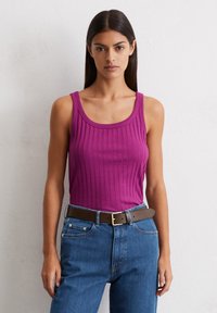 Dopasowany prążkowany top w intensywnej magencie, z szerokimi ramiączkami i dekoltem w kształcie łódki, zestawiony z dżinsami z wysokim stanem w kolorze niebieskim oraz brązowym paskiem.