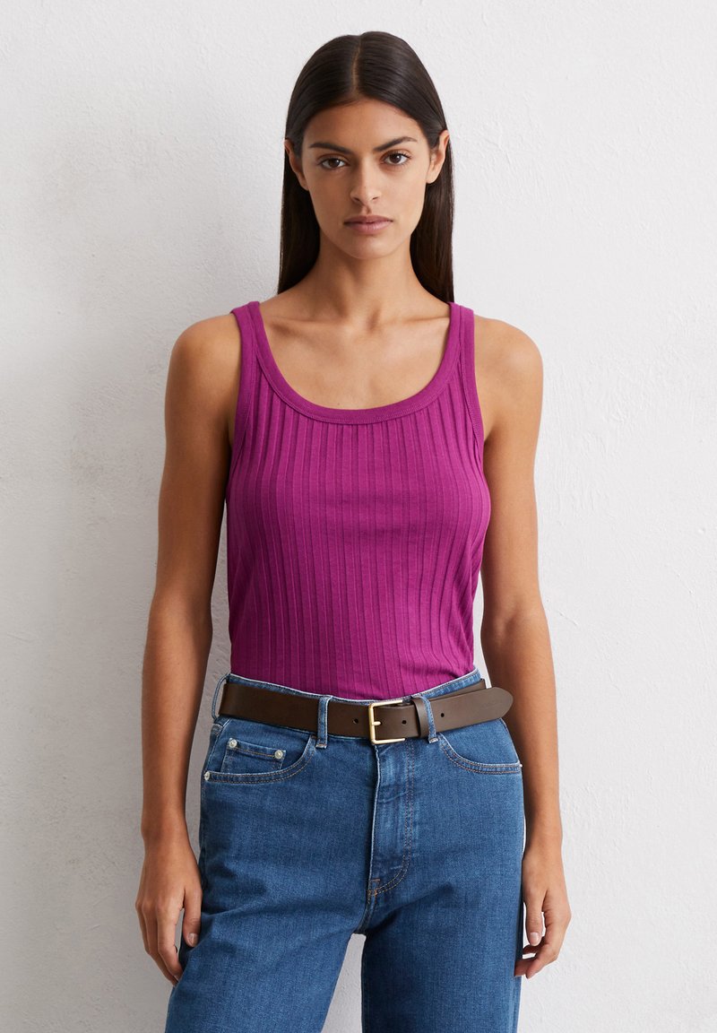 Dopasowany prążkowany top w intensywnej magencie, z szerokimi ramiączkami i dekoltem w kształcie łódki, zestawiony z dżinsami z wysokim stanem w kolorze niebieskim oraz brązowym paskiem.