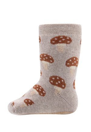 Beżowa dziana skarpetka z wzorem brązowych grzybów z białymi plamkami rozsianymi po całej powierzchni.