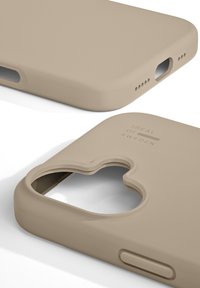 Beige silikon deksel til telefon med utskjæring for kamera, jevn tekstur, avrundede kanter og logo med teksten "IDEAL OF SWEDEN."