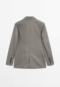 Blazer gris tailleur avec un motif à carreaux subtil, manches longues avec quatre boutons noirs sur chaque manchette, et une fente centrale au dos.