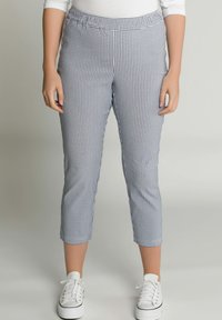 Blauw-witte geruite capri broeken met een elastische tailleband en een getailleerd ontwerp, gecombineerd met witte sneakers op een lichte achtergrond.
