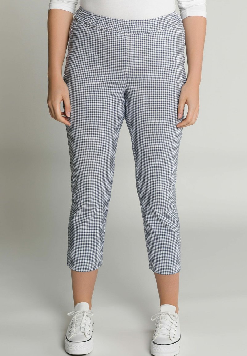 Blauw-witte geruite capri broeken met een elastische tailleband en een getailleerd ontwerp, gecombineerd met witte sneakers op een lichte achtergrond.