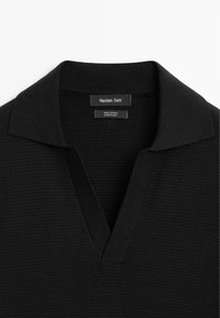 Pullover in cotone nero con un design a maglia testurizzata, dotato di un classico scollo a V e di un colletto nero uniforme. Etichette visibili all'interno del capo.