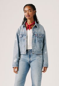 Denim jakk, millel on hõbedased kaunistused, lühendatud disain, klassikaline krae, nööbid ees ja kaks rinna taskut. Kombineeritud sobivate kõrgema vööjoonega teksadega.