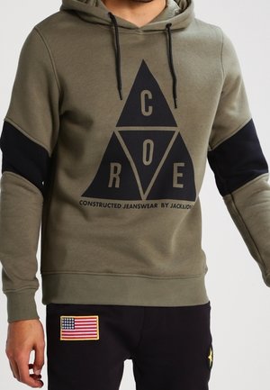 Olivgrön hoodie med svarta ärmdetaljer, med en stor svart triangel-logotyp och text. Tillverkad av mjukt tyg med dragsko i huvan.