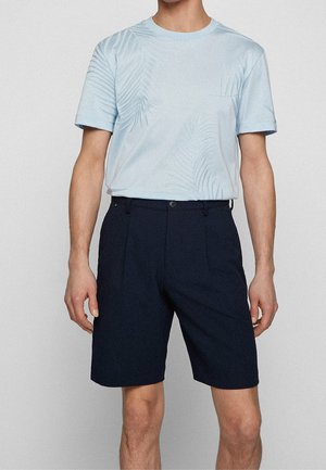 Lichtblauw T-shirt met korte mouwen en een subtiel palmbladpatroon, gecombineerd met donkerblauwe shorts van een gestructureerde stof met voorzakken.