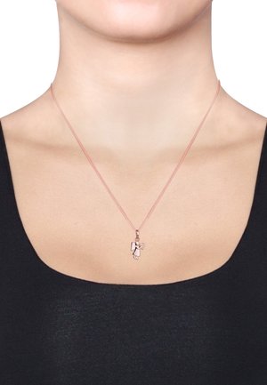 Rose gold necklace with a chain design featuring an angel pendant holding a book. Worn against a black top, highlighting the pendant.
