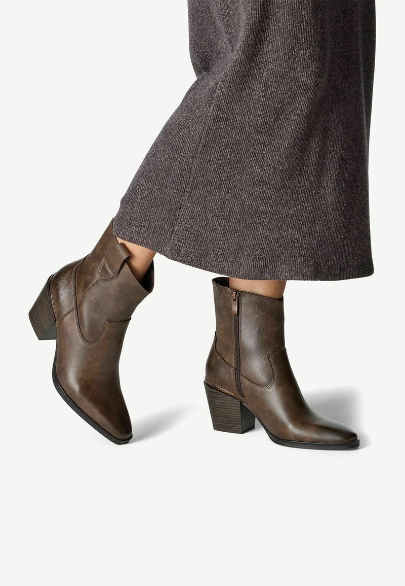 Bottines en cuir marron avec un bout pointu, dotées d'une fermeture éclair latérale et d'un talon empilé. Tige texturée avec une finition lisse.