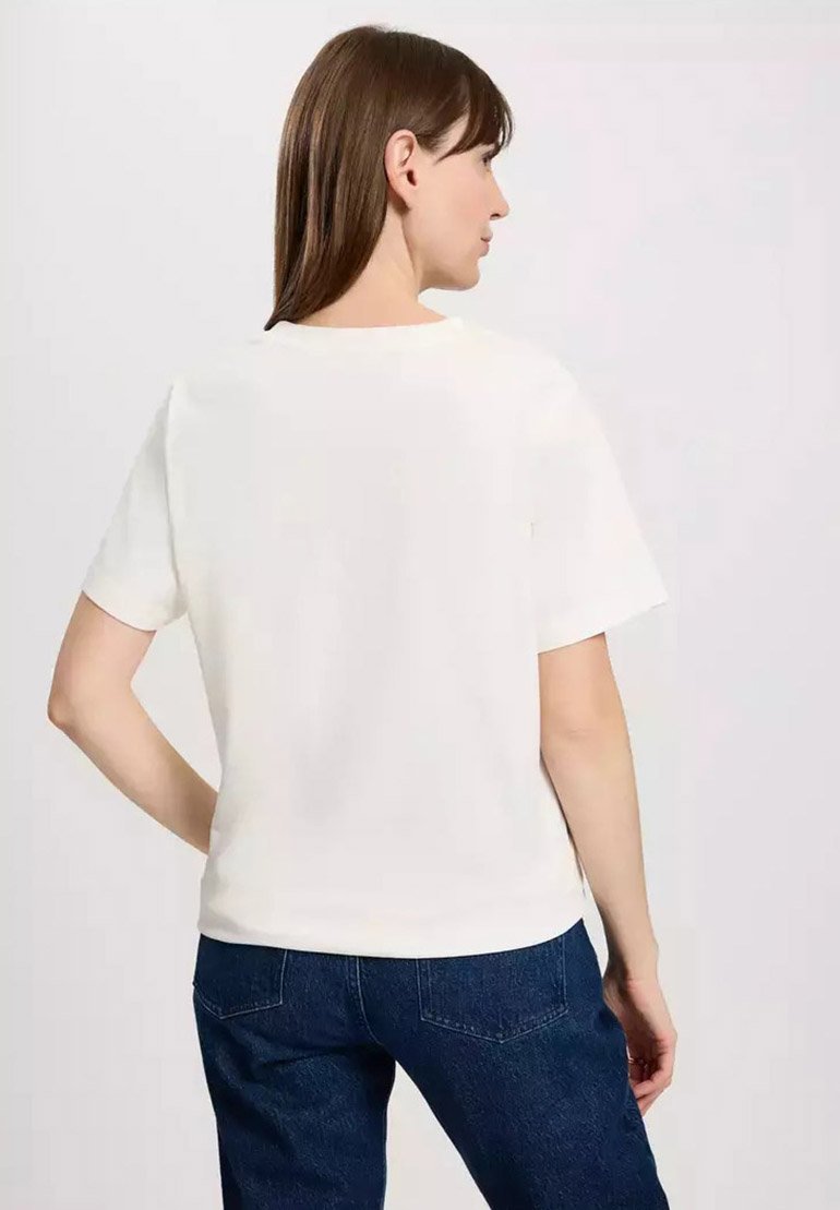 Biała koszulka z krótkim rękawem, okrągłym dekoltem, gładką fakturą, luźnym kroju, noszona z ciemnoniebieskimi dżinsami, pokazująca widok z tyłu.