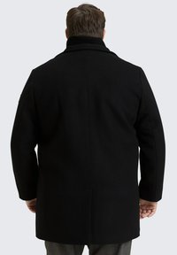 Czarny wełniany płaszcz z wysokim kołnierzem i uporządkowanym wzorem. Ma prostą sylwetkę i długość do kolan, z detalami w postaci prążkowanego kołnierza.
